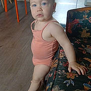 Elysianna participe au concours pour gagner de l'argent avec cette photo : toddler, child, indoor, sofa, floral_pattern, toy, stuffed_animal, elephant_toy, wooden_floor, orange_chair, table, blue_eyes, peach_outfit, hand_on_sofa, curly_hair, home_interior, cabinet, doorway, flooring, person