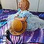 toddler, child, blue_dress, hat, straw_hat, bed, bedspread, butterfly_pattern, smiling, happy, indoor, person, clothing, fabric, hair, cute, sitting, portrait, young_child, playful