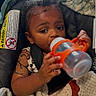 Quilan is registered to the contest to win money with this photo: baby, child, car_seat, sippy_cup, blanket, lion_design, curly_hair, indoor, cute, comfort, toddler, clothing, seat_belt, portrait, infant, drinking, baby_bottle, soft_texture, warm, young_child