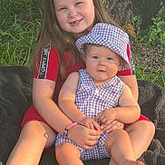 Timothy joined the competition — help win amazing prizes! child, baby, sibling, sitting, smiling, outdoor, tree, grass, blanket, portrait, family, infant, toddler, hat, dress, red_clothing, checkered_pattern, summer, cuddling, sunlight