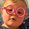 Timothy is registered to the contest to win money with this photo: child, toddler, baby, portrait, face, glasses, pink_glasses, curly_hair, blonde_hair, expression, serious, close_up, indoor, shirt, tiger_shirt, clothing, sitting, camera, colorful, funny