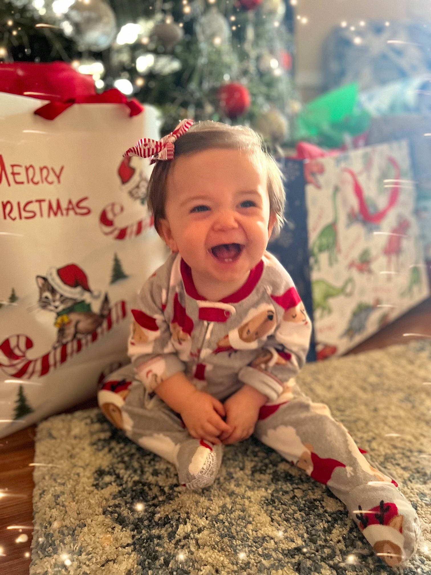 Everlee is registered to the contest to win money with this photo: baby, baby_toddler_clothing, carmine, child, christmas, christmas_decoration, christmas_ornament, christmas_tree, event, face, facial_expression, flooring, fun, happy, holiday, person, sitting, smile, toddler, tree