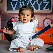 Giulia a rejoint le concours — aidez-le/la à gagner de superbes lots ! toddler, child, baby, white_clothing, pencil, barefoot, smiling, portrait, indoor, clock, suitcase, alphabet, background, hair_clip, cute, sitting, playful, soft_surface, happy, decor