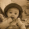 baby, child, hat, hand, fingers, adult_hand, vintage, sepia, portrait, indoors, cute, infant, clothing, plaid, expression, face, person, sitting, warm_tone, grip