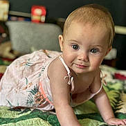 Marielle is registered to the contest to win money with this photo: baby, child, crawling, dress, quilt, indoor, curious, cute, infant, person, young_child, smiling, skin, face, hand, green, pattern, bedroom, home, portrait