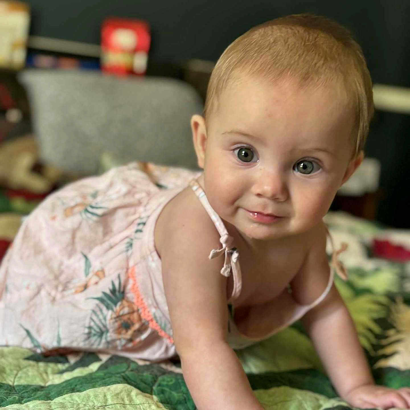 Marielle is registered to the contest to win money with this photo: baby, bedroom, child, crawling, curious, cute, dress, face, green, hand, home, indoor, infant, pattern, person, portrait, quilt, skin, smiling, young_child