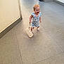 toddler, child, smiling, romper, handbag, footwear, sandals, hair, walking, corridor, floor_tiles, wall, outdoor, daylight, person, cute, happy, fashion, small_bag, baby