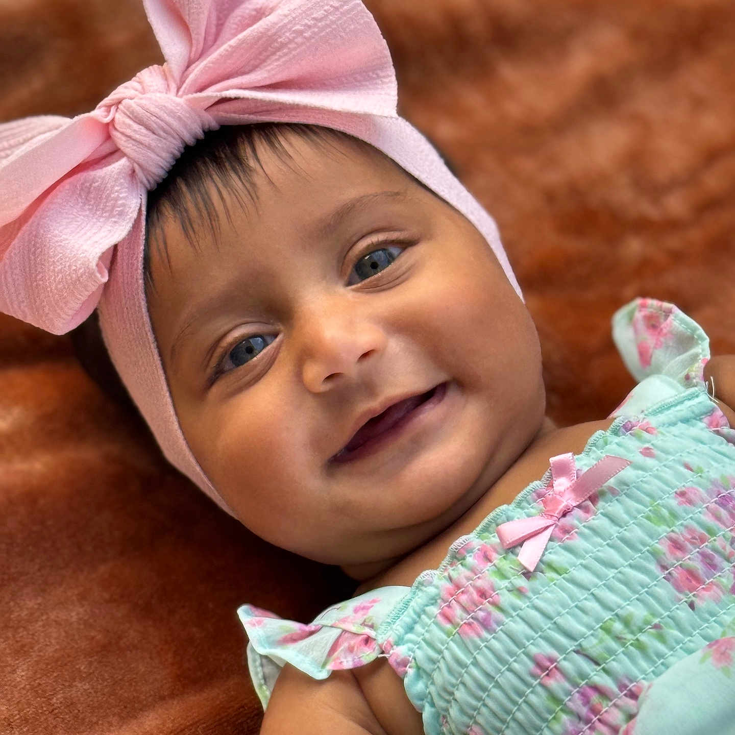 Aleezay is registered to the contest to win money with this photo: adorable, baby, blue_eyes, child, close_up, cute, dress, face, floral_pattern, happy, headband, infant, lying_down, pastel_colors, person, pink_bow, portrait, skin, smile, soft_blanket