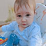 Maxime a rejoint le concours — aidez-le/la à gagner de superbes lots ! baby, child, infant, high_chair, plush_toy, dinosaur_toy, blue_clothing, curious_expression, close_up, indoor, cute, soft_lighting, face, young_child, seated, adorable, portrait, looking_at_camera, toddler, small_hands