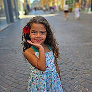 Alîna a rejoint le concours — aidez-le/la à gagner de superbes lots ! background_blur, child, cobblestone, curly_hair, daylight, dress, floral_pattern, flower, girl, happy, outdoor, people, portrait, posing, sandals, sidewalk, smile, street, summer, urban