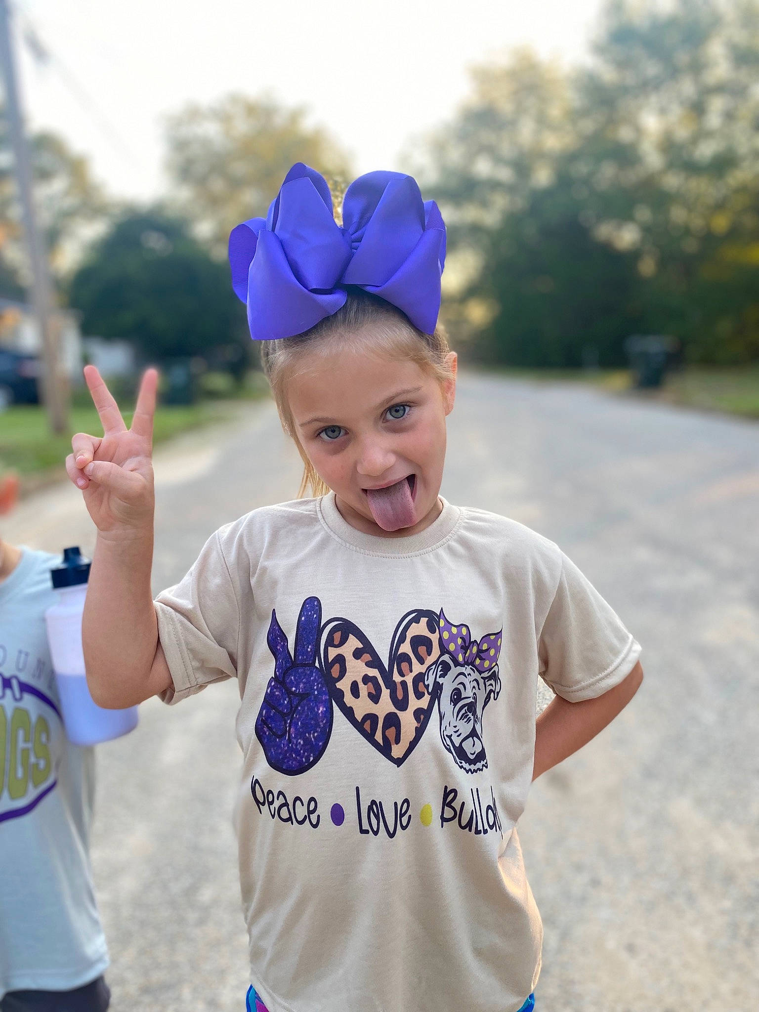 Brynlee joined the competition — help win amazing prizes! arm, blue, cap, cool, face, facial_expression, fun, gesture, grass, hairstyle, happy, headgear, leaf, person, photograph, pink, sky, sleeve, summer, t_shirt