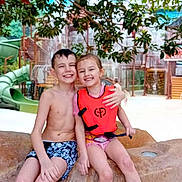 Djemy a rejoint le concours — aidez-le/la à gagner de superbes lots ! child, children, smiling, water_park, life_vest, swimwear, rock, slide, greenery, outdoor, happy, friendship, summer, playful, barefoot, fun, water, nature, posing, sitting