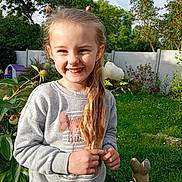 Cassie participe au concours pour gagner de l'argent avec cette photo : child, girl, smile, long_hair, gray_sweater, flower, garden, greenery, outdoor, sunlight, playful, bunny_statue, nature, grass, fence, happy, portrait, person, young, cute