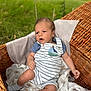 baby, infant, wicker_basket, blanket, outdoor, grass, blue_shirt, striped_romper, socks, cute, portrait, child, young, soft_light, nature, relaxing, comfort, expression, small_hands, footwear