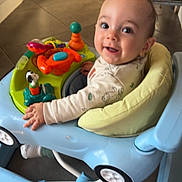 Keyden participe au concours pour gagner de l'argent avec cette photo : baby, walker, toy, smile, child, indoor, floor, cushion, play, happy, person, furniture, clothing, face, head, expression, colorful, seat, kitchen, curious