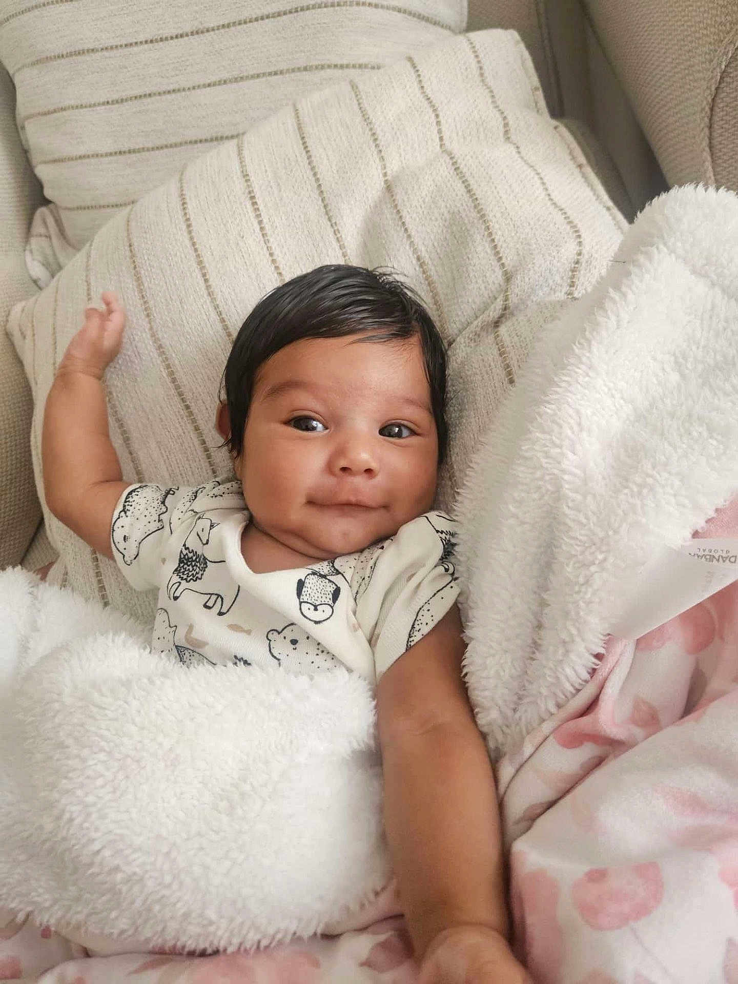 Kency joined the competition — help win amazing prizes! baby, infant, smile, blanket, pillow, onesie, animal_print, cozy, cute, face, arm, lying_down, soft_texture, indoor, child, portrait, happy, skin, black_hair, resting