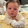 baby, infant, child, portrait, wide_eyed, surprised, bedhead, face, eyes, indoors, cushion, blanket, pajamas, mittens, seated, close_up, bedroom, soft_lighting, cartoon_pattern, adorable