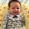 baby, infant, child, smiling, happy, portrait, sitting, floral_cushion, yellow, blanket, teddy_bears, patterned_clothing, bow, indoors, cozy, bedhead, face, eyes, baby_seat, photography