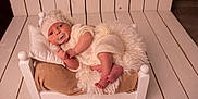 Xavi participe au concours pour gagner de l'argent avec cette photo : baby, infant, pacifier, knitted_clothing, hat, bed, pillow, blanket, wooden_floor, cozy, cute, indoors, portrait, relaxing, small_bed, child, newborn, soft_texture, warm_colors, lying_down