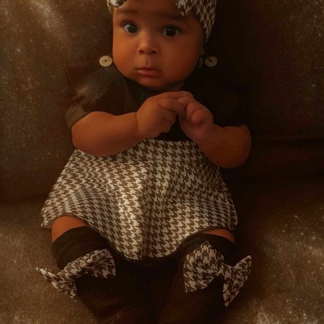 Hayvn is registered to the contest to win money with this photo: adorable, baby, bow, brown, child, clothing, couch, cozy, cute, expression, fabric, hands, headband, houndstooth, indoor, infant, outfit, portrait, sitting, soft_light