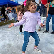Alexandra is registered to the contest to win money with this photo: child, girl, pink_bow, smiling, holding_cup, snow, outdoor, people, tent, blue_sky, casual_clothing, jeans, sneakers, playful, crowd, event, daytime, happy, portrait, fun