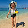 child, girl, beach, sunhat, swimsuit, sand, ocean, water, sky, sunlight, shadow, smile, summer, vacation, outdoor, toy, yellow, happy, play, holiday