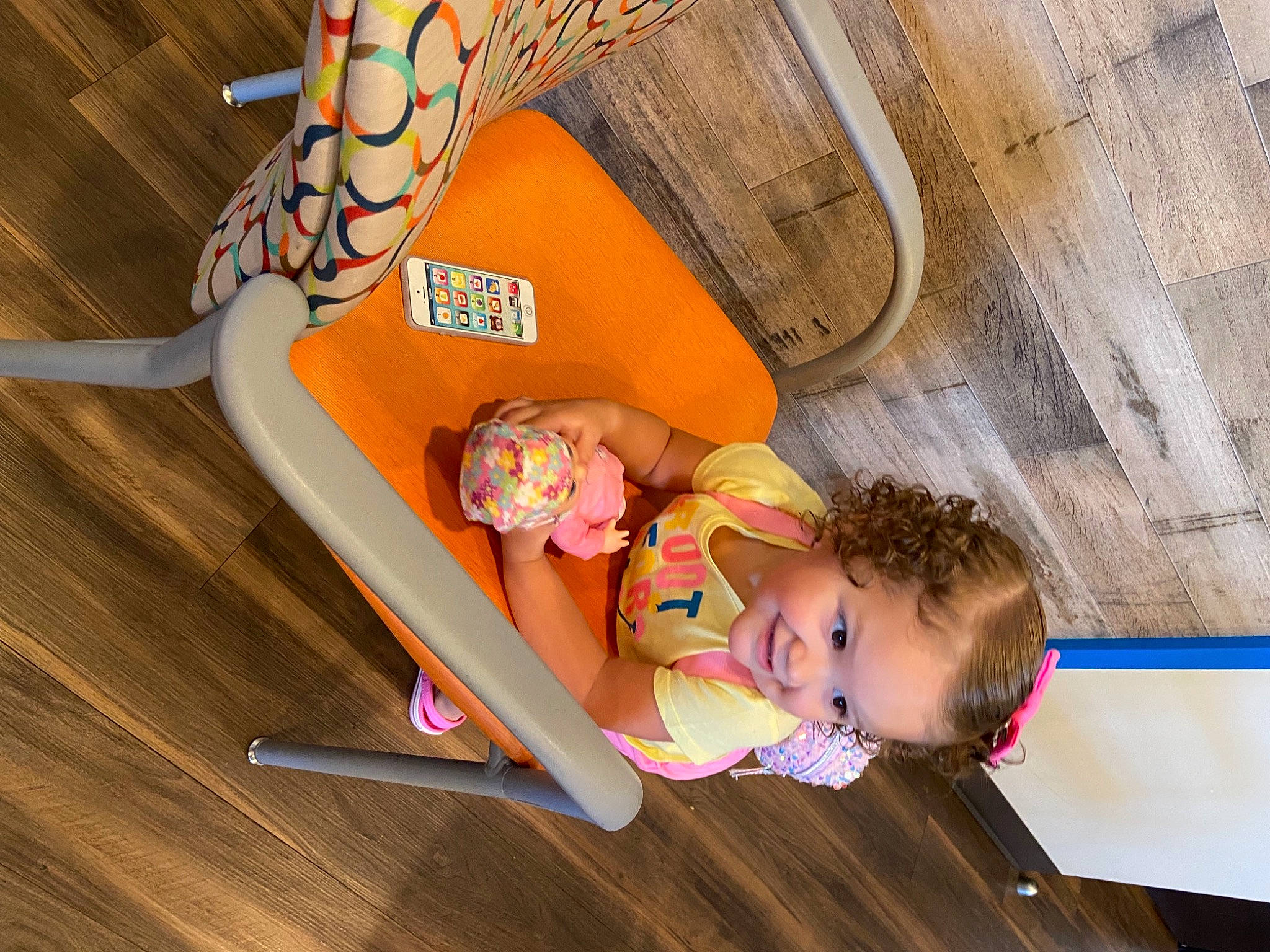 Kenna is registered to the contest to win money with this photo: baby, baby_products, child, flooring, fun, hand, happy, hardwood, human_leg, joy, leisure, orange, peach, person, play, recreation, room, sitting, thigh, toddler