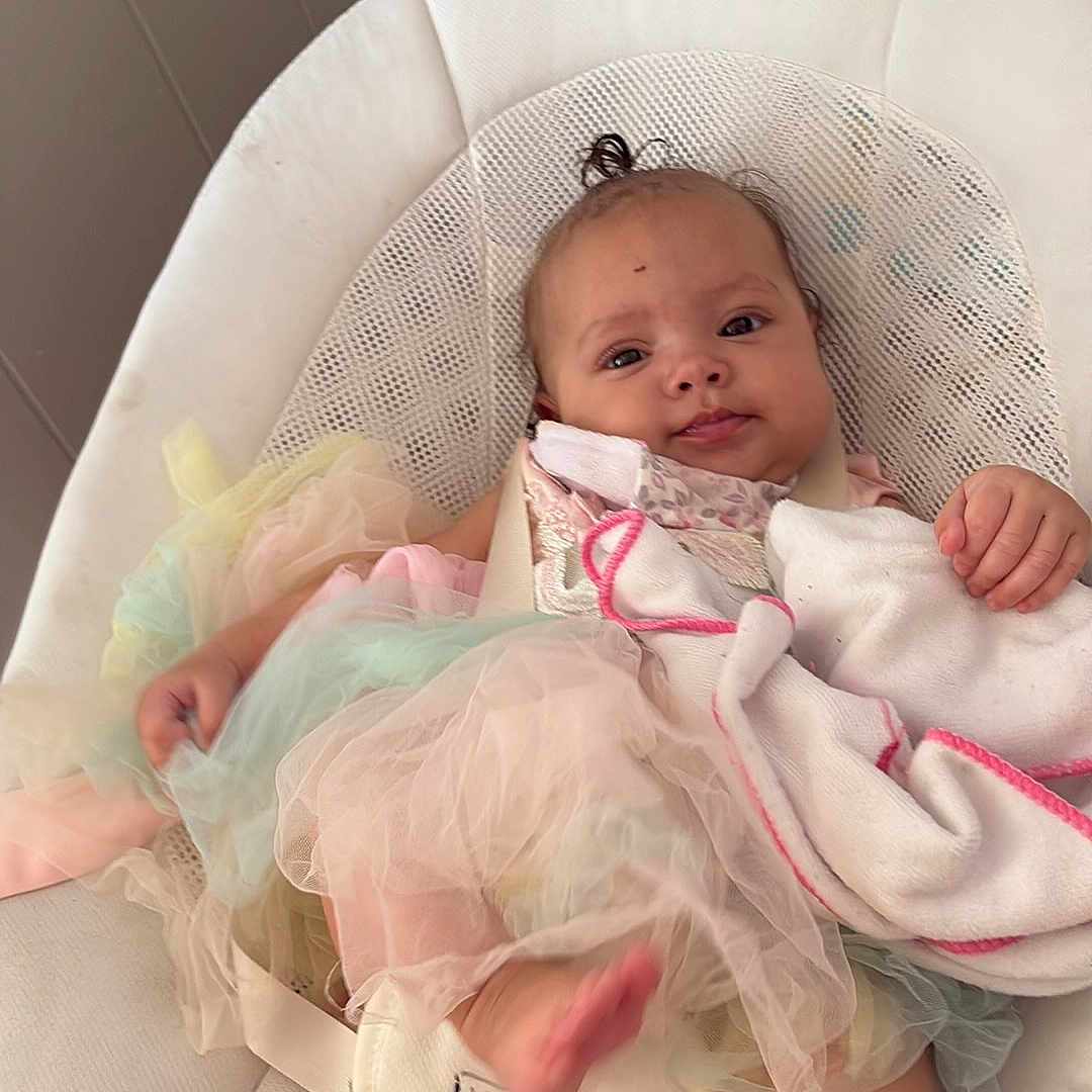 Brianna joined the competition — help win amazing prizes! baby, infant, tutu, blanket, baby_seat, indoor, relaxed, child, person, cushion, floor, wood_floor, clothing, head, face, foot, hand, soft_toys, home, curly_hair