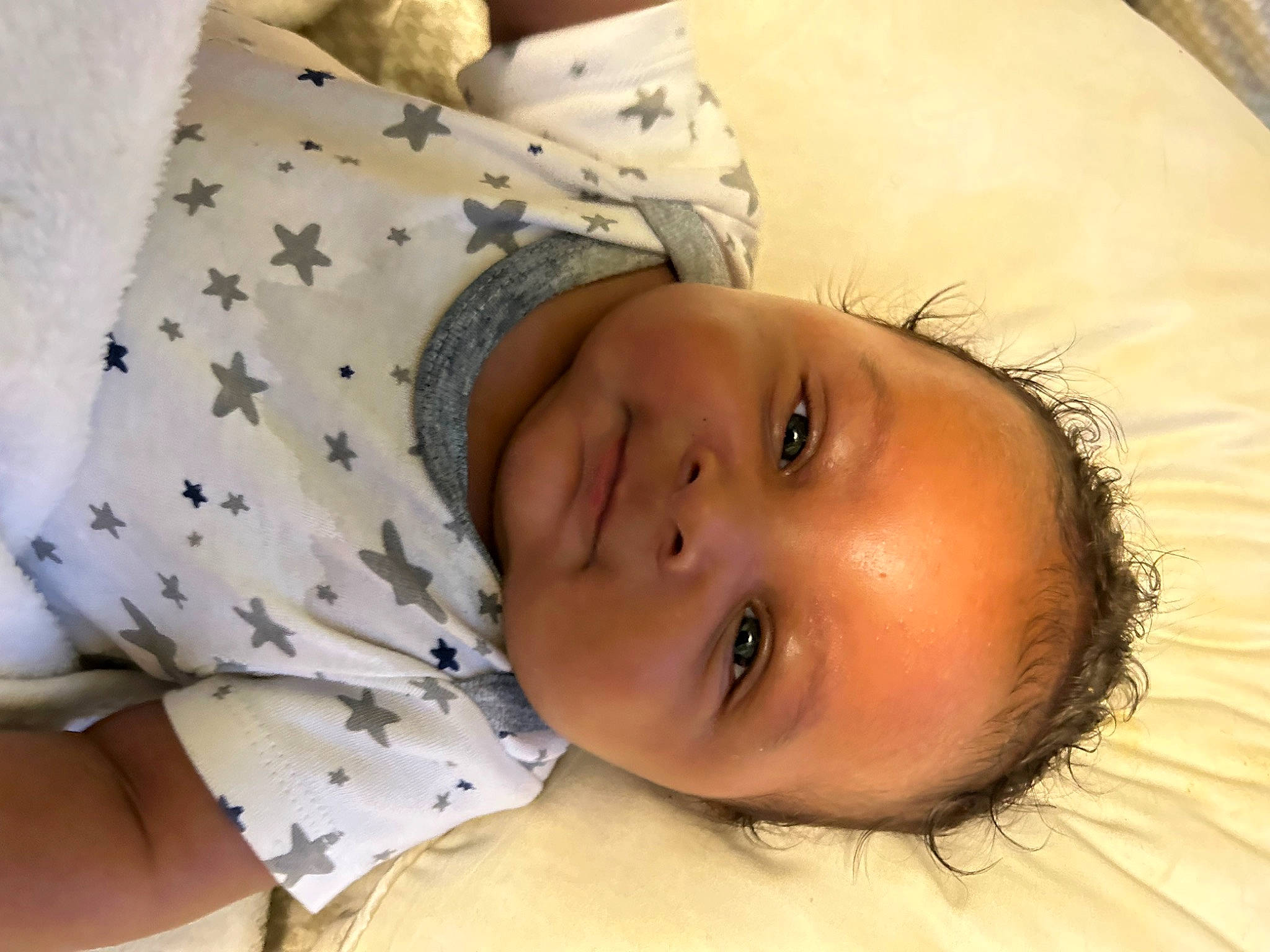 Jakari is registered to the contest to win money with this photo: baby, baby_toddler_clothing, cheek, child, comfort, eye, eyelash, face, happy, human_body, iris, linens, lip, nose, pattern, person, room, skin, smile, textile