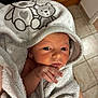 newborn, baby, towel, hooded_towel, bear_design, infant, wrapped, cute, soft_texture, hand, face, eyes, indoor, tile_floor, wooden_stairs, skin, person, portrait, cozy, closeup