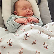 Anna a rejoint le concours — aidez-le/la à gagner de superbes lots ! baby, newborn, sleeping, blanket, infant_seat, hands, face, head, clothing, bedding, floral_pattern, portrait, close_up, indoor, soft_light, peaceful, cozy, family, tiny, resting