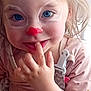 toddler, child, face_paint, blue_eyes, finger_in_mouth, pink_clothing, polka_dot, pacifier_clip, close_up, curly_hair, playful, smile, indoor, person, cute, young_child, portrait, hand, baby, innocent