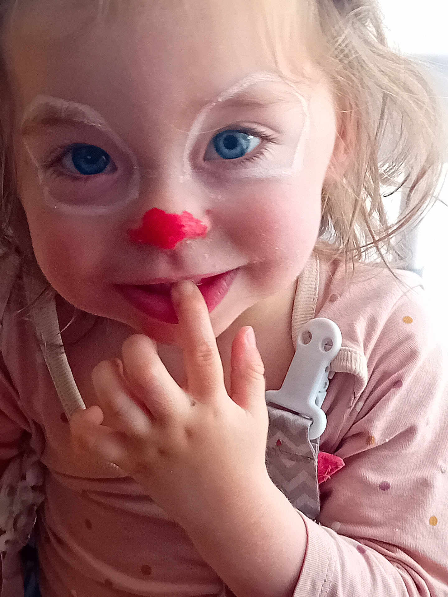 Anna participe au concours pour gagner de l'argent avec cette photo : toddler, child, face_paint, blue_eyes, finger_in_mouth, pink_clothing, polka_dot, pacifier_clip, close_up, curly_hair, playful, smile, indoor, person, cute, young_child, portrait, hand, baby, innocent