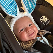 Grayson is registered to the contest to win money with this photo: baby, baby_boy, blue, bunny_ears, car_seat, checkered_pattern, child, close_up, clothing, cute, face, happy, headwear, indoor, infant, portrait, seatbelt, smiling, soft_texture, young_child