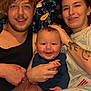 baby, adult, family, smiling, indoor, blanket, tattoo, casual_clothing, couch, portrait, happy, hand_holding, person, young_adult, infant, home, relaxed, toddler, face, tshirt