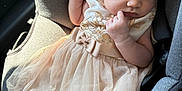 Paris is registered to the contest to win money with this photo: baby, sleeping, car_seat, dress, headband, bow, infant, child, clothing, fabric, seatbelt, car_interior, cute, adorable, peaceful, portrait, soft_light, tulle, young_child, resting