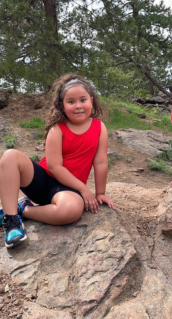 Annaliese is registered to the contest to win money with this photo: bedrock, eye, flash_photography, forest, fun, grass, hairstyle, happy, joy, landscape, leisure, people_in_nature, person, plant, recreation, shorts, thigh, toddler, tree, trunk