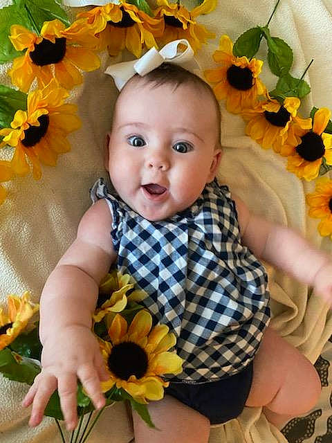 Hailey joined the competition — help win amazing prizes! baby, baby_toddler_clothing, botany, dress, face, facial_expression, flower, hairstyle, hand, happy, iris, leaf, orange, organ, person, petal, photograph, plant, product, textile