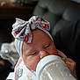 baby, bottle, feeding, headband, bow, infant, sleepy, milk, bib, cute, pastel, animal_print, hand, face, portrait, indoor, soft_light, cozy, child, newborn