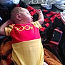 baby, sleeping, onesie, pooh, blanket, remote_control, infant, clothing, cute, rest, home, relaxation, child, cozy, soft, person, indoors, peaceful, small, lying_down
