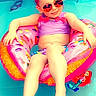 child, pool, floatie, donut, sunglasses, swimwear, water, toy, beach_ball, relaxing, summer, outdoor, fun, playful, smiling, vacation, floating, sunny, leisure, cute