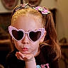 child, girl, sunglasses, heart_shaped, pink, headband, flower, hair, pigtails, blowing_kiss, black_shirt, indoor, portrait, cute, playful, closeup, face, fashion, accessory, expression