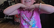 Luna is registered to the contest to win money with this photo: child, girl, smiling, glasses, bracelet, necklace, pink_shirt, barbie, indoor, flooring, wall_art, shelf, clothing, shorts, playful, happy, person, home, decor, portrait