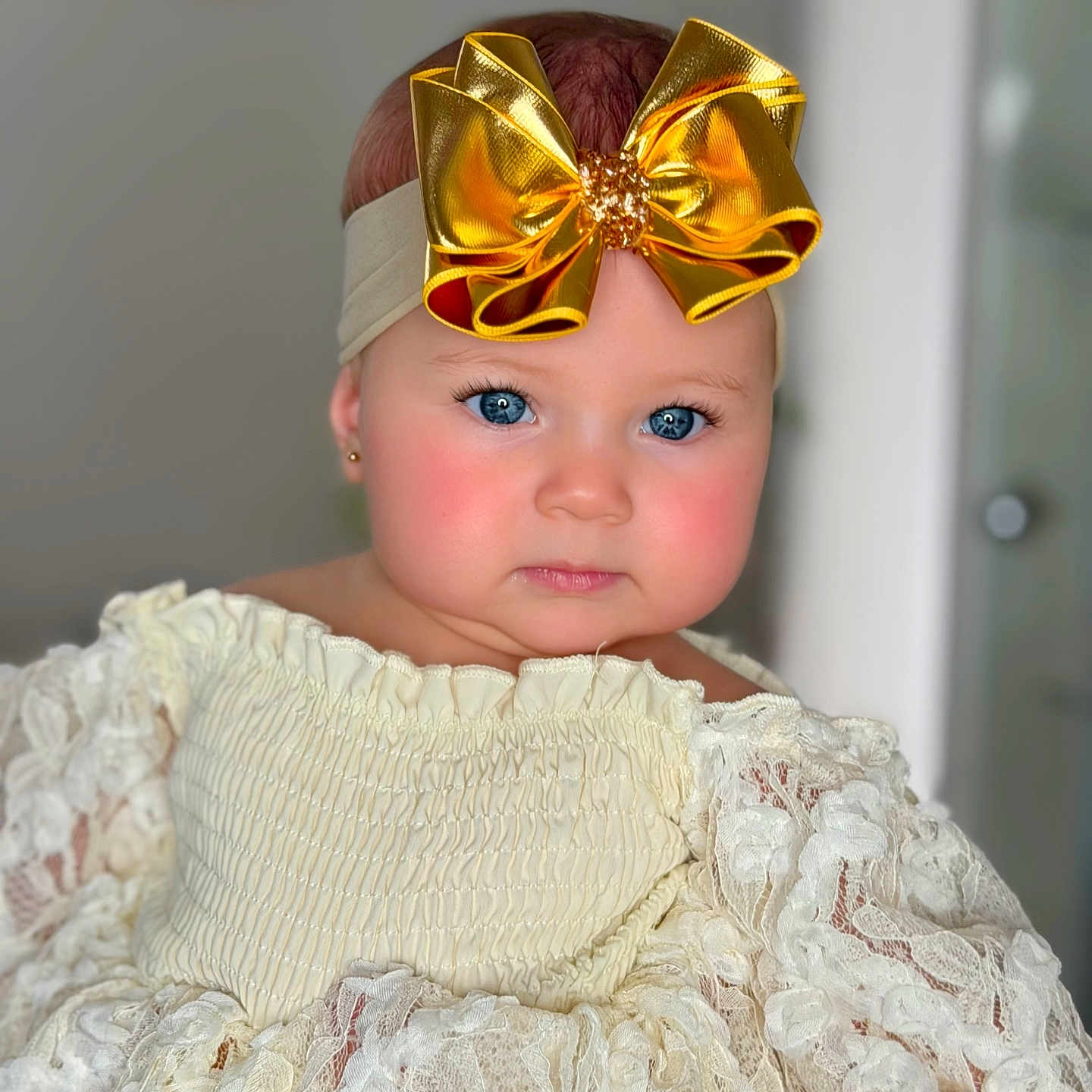 émie Burghard a rejoint le concours — aidez-le/la à gagner de superbes lots ! adorable, baby, blue_eyes, child, closeup, clothing, cream_color, cute, expression, face, fashion, golden_bow, headband, indoor, infant, lace_dress, person, portrait, rosy_cheeks, young