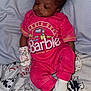 baby, infant, sleeping, pink_clothing, barbie, bow, socks, blanket, bed, curly_hair, cute, resting, indoor, child, toddler, soft_lighting, patterned_sheet, gloves, small_child, portrait