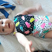 Zadie joined the competition — help win amazing prizes! baby, infant, child, smiling, colorful_clothing, popsicle_pattern, lying_down, reaching_hand, white_bedspread, towel, tablet, indoors, happy, cute, playful, skin, face, arm, leg, closeup