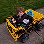 Rebel joined the competition — help win amazing prizes! child, toy, dump_truck, yellow, outdoor, grass, concrete, happy, smiling, curly_hair, play, vehicle, kid, casual_clothing, sidewalk, daylight, small, person, fun, park