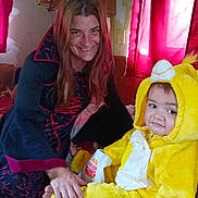 Rebel is registered to the contest to win money with this photo: woman, child, costume, yellow, lion, burger_king, bag, indoor, curtains, red, smile, bed, plush, person, clothing, furniture, home, portrait, happy, casual
