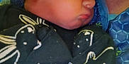 Harley is registered to the contest to win money with this photo: baby, sleeping, infant, blanket, clothing, person, closeup, face, rest, child, cute, cozy, comfort, newborn, holding, soft, warm, pattern, animal_print, indoor