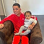 Kays participe au concours pour gagner de l'argent avec cette photo : brown, casual, chair, child, clothing, curly_hair, door, family, floor, holding, indoor, man, person, portrait, red, seated, smile, toddler, tracksuit, young